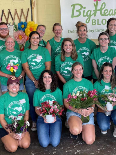 Hyland employees pose with their volunteer flower arrangements at BigHearted Blooms.